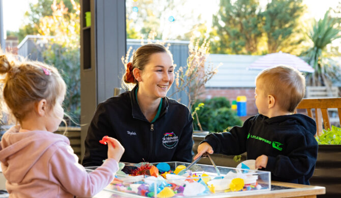 A St Nicholas Early Education educator with a child in St Nicholas' toddler program, playing outside with sensory items