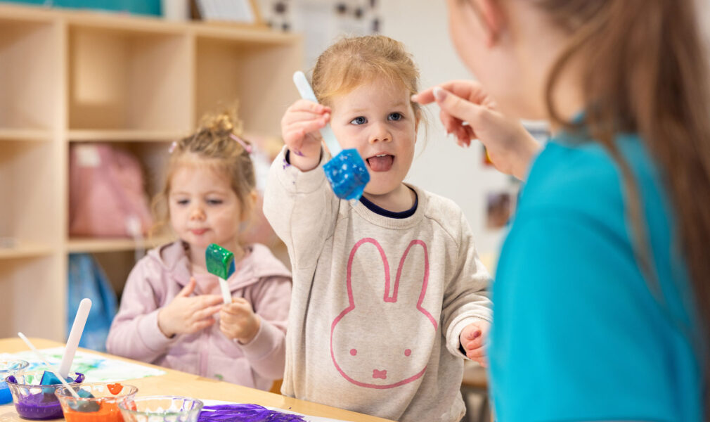 Children and educator painting together at Lochinvar early education centre