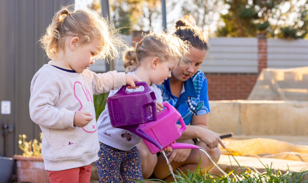 Children and educator tending to gardens outside at Lochinvar early education centre
