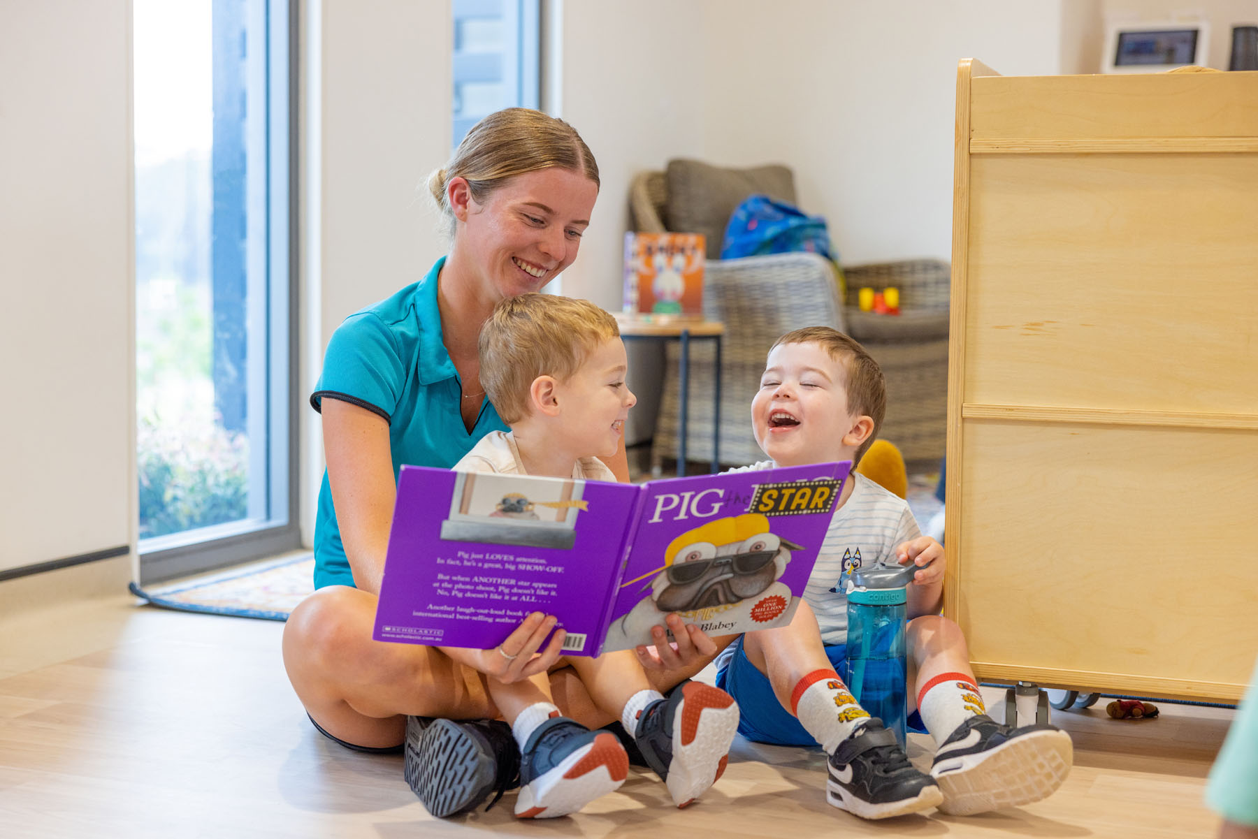 Children and educator reading a book at Chisholm early education centre