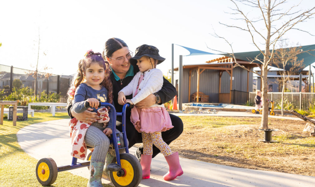 Two children and educator on bike at Gillieston Heights early education centre