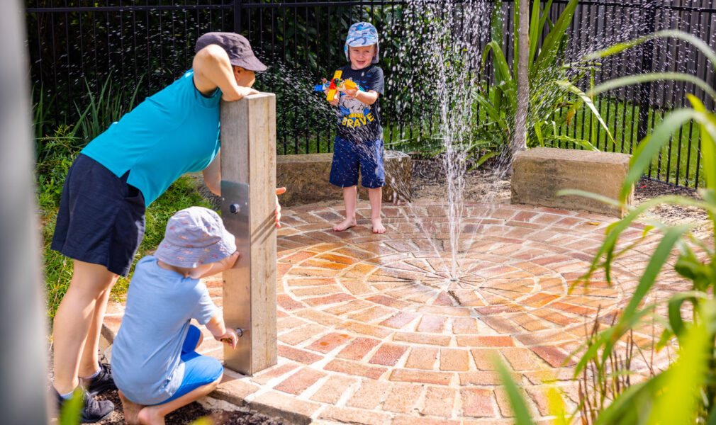 Children and educator playing in water fountain at Maitland early education centre