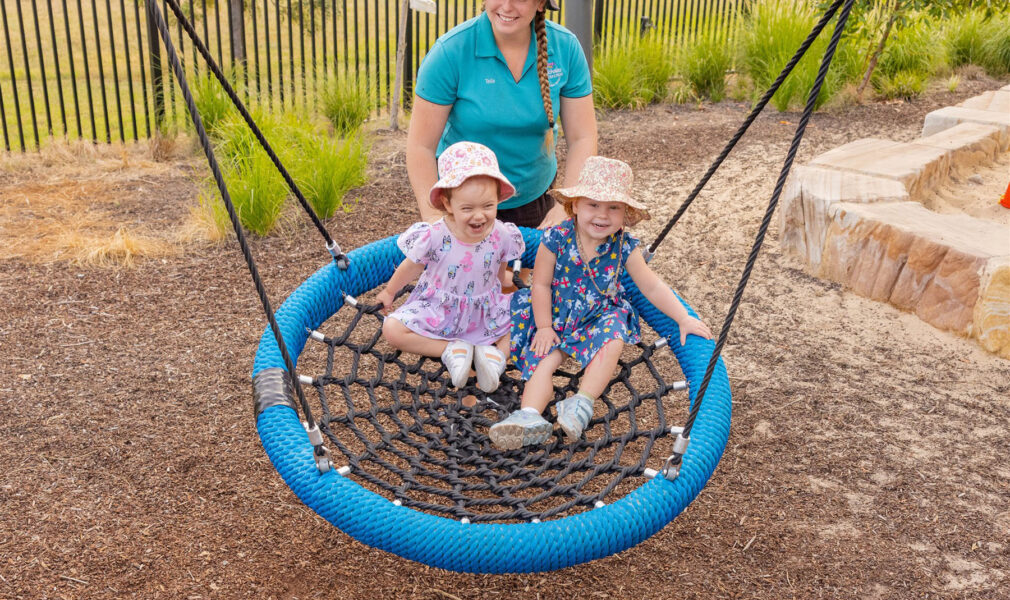 Children and educator on basket swing outside at Muswellbrook early education centre