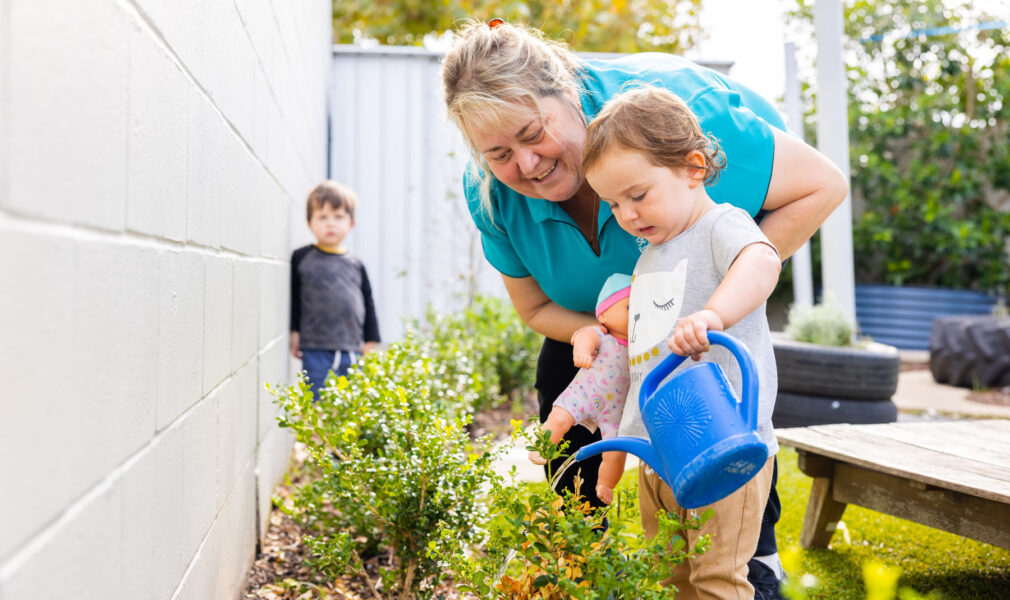 Educator and children tending to gardens together outside at Newcastle West early education centre