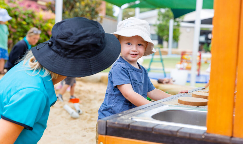 Child and educator playing in mud kitchen together outside at Newcastle West early education centre