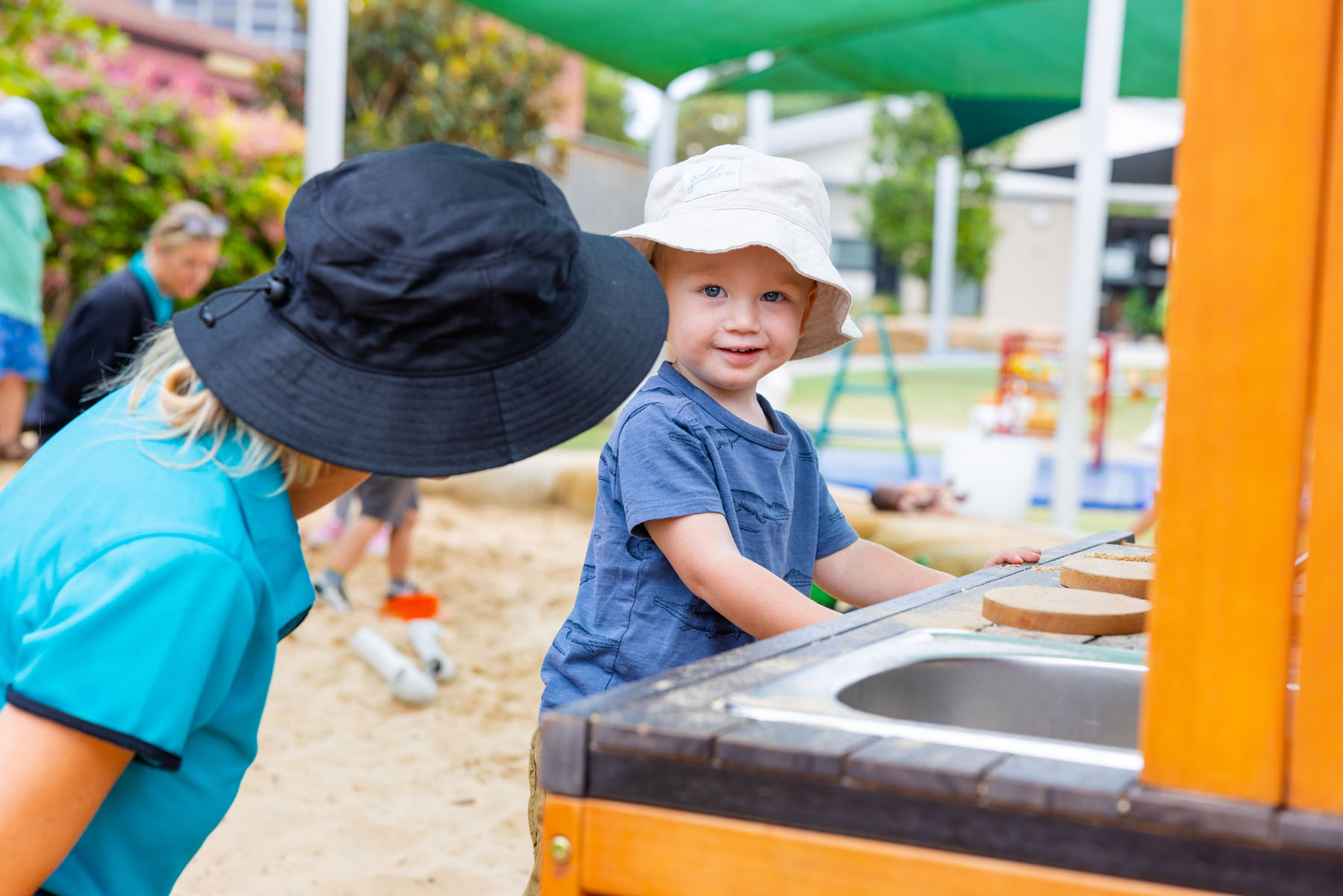 Child and educator playing in mud kitchen together outside at Newcastle West early education centre