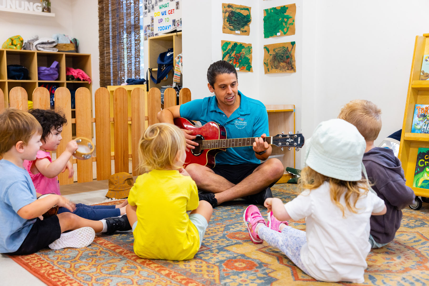 Male educator playing guitar with children at Newcastle West early education centre