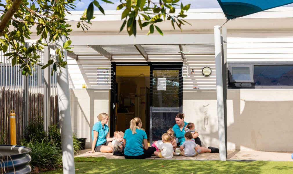 Educators and children sitting outside together at Newcastle West early education centre