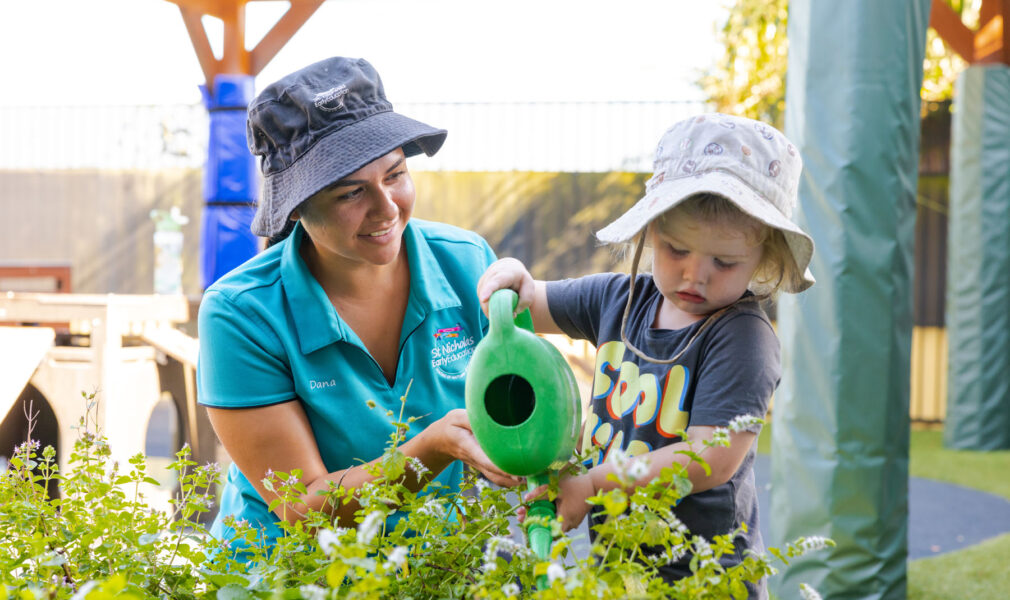 Educator and child tending to gardens together outside at Raymond Terrace early education centre