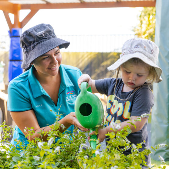 Educator and child tending to gardens together outside at Raymond Terrace early education centre