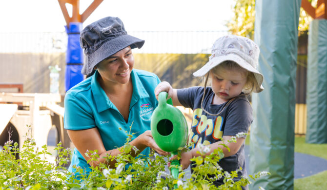 Educator and child tending to gardens together outside at Raymond Terrace early education centre