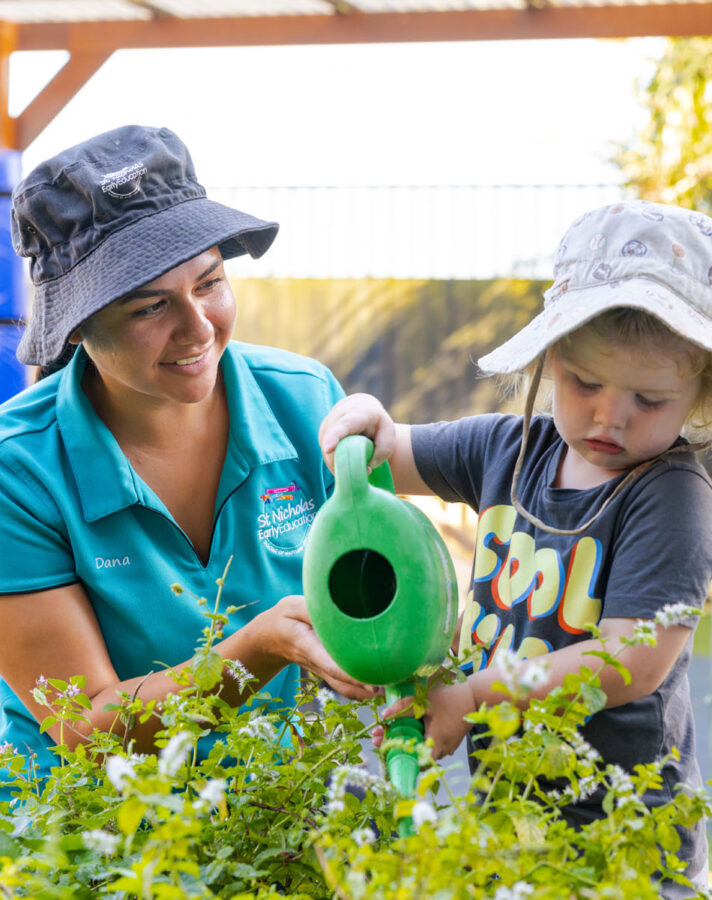 Educator and child tending to gardens together outside at Raymond Terrace early education centre