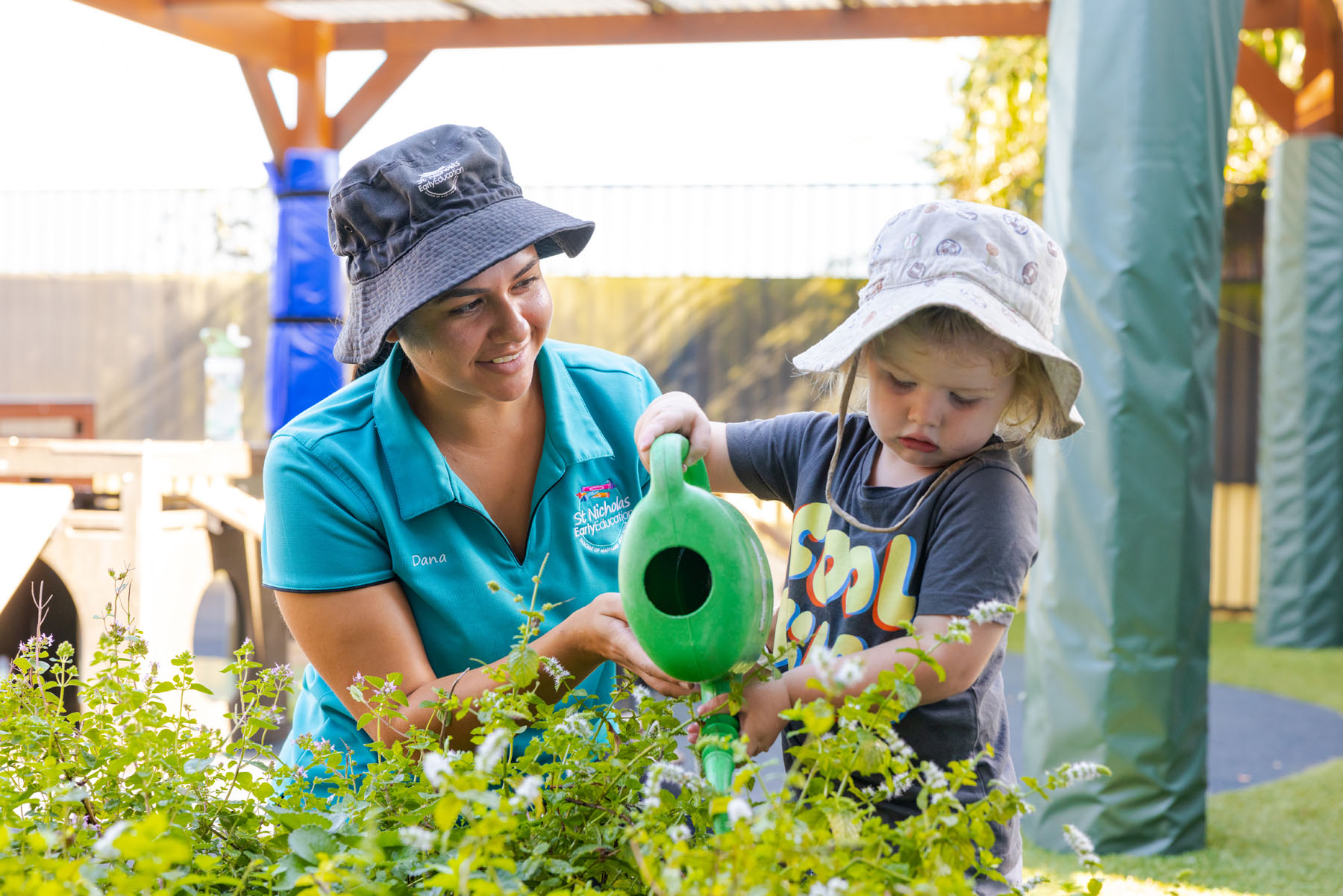 Educator and child tending to gardens together outside at Raymond Terrace early education centre