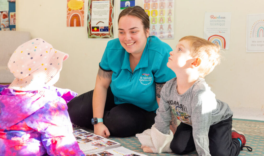 Educator and children reading floorbook inside at Singleton early education centre