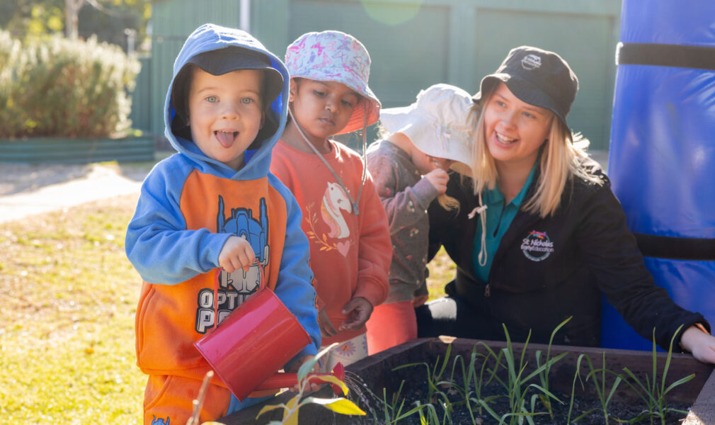 Children and educator tending to gardens outside at Singleton early education centre