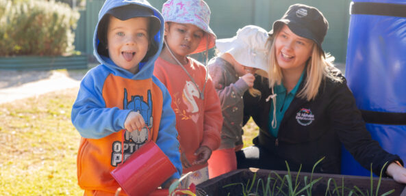 Children and educator tending to gardens outside at Singleton early education centre