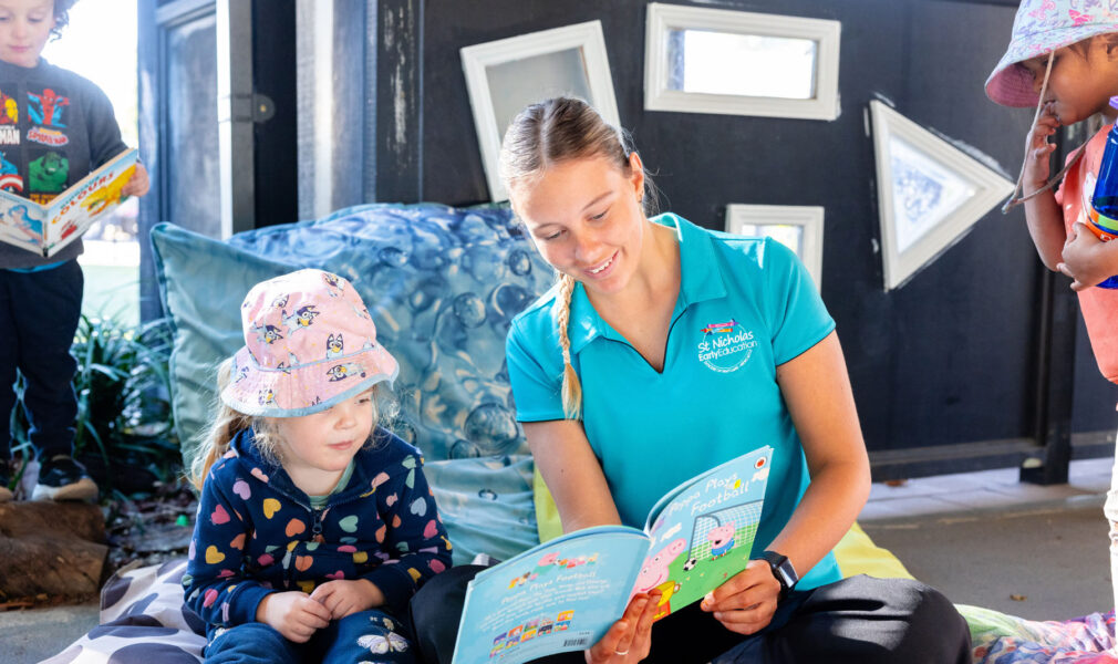 Educator reading to child outside at Singleton early education centre