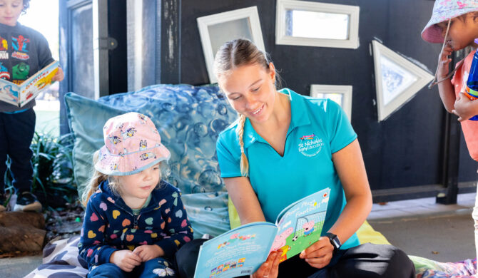 Educator reading to child outside at Singleton early education centre