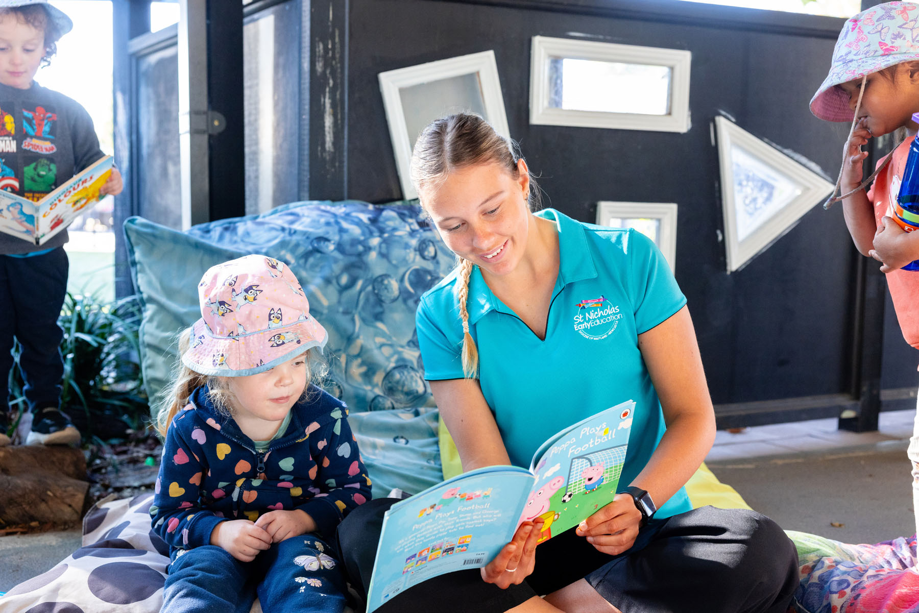 Educator reading to child outside at Singleton early education centre