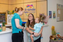 A St Nicholas educator interacting with a parent/carer and preschool child