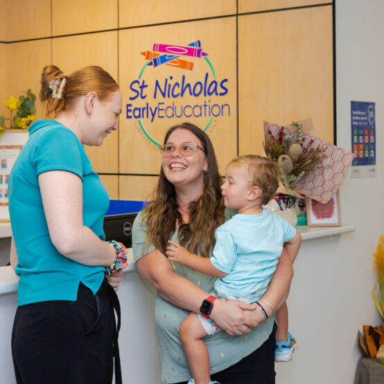 A St Nicholas educator interacting with a parent/carer and preschool child