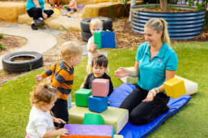 St Nicholas work-based trainee playing with foam blocks with children at one of our early childhood centres