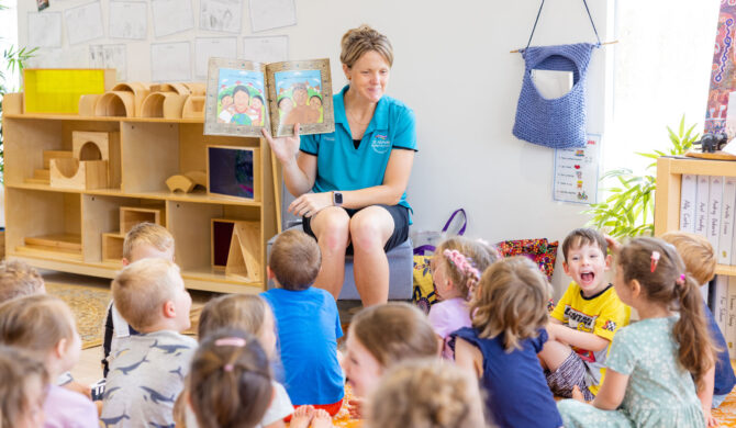 A career Early Childhood Teacher with St Nicholas Early Education reading a book to a room of children.