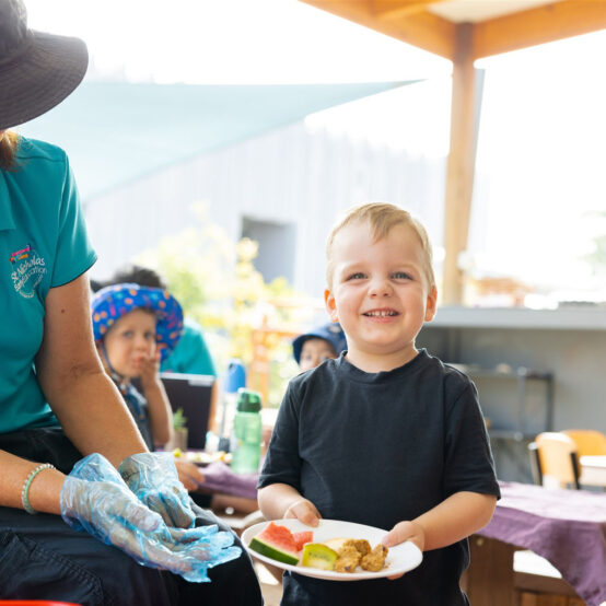 A child care cook with St Nicholas Early Education serving a child food