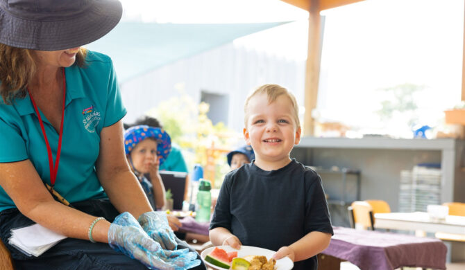 A child care cook with St Nicholas Early Education serving a child food